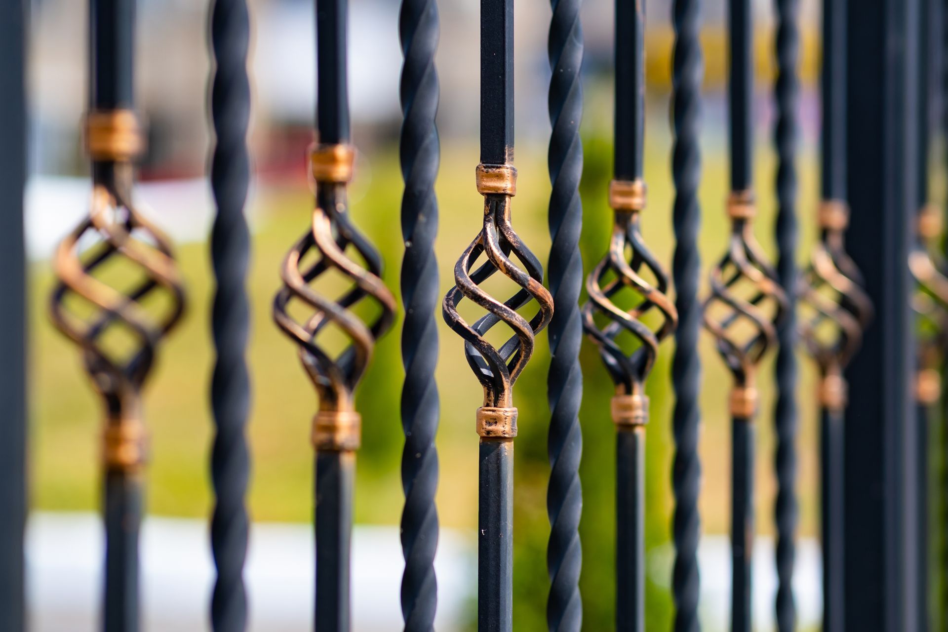 Ornamental iron fence with twisted black bars and gold diamond accents outdoors. Ornamental iron fence with twisted black bars and gold diamond accents outdoors.