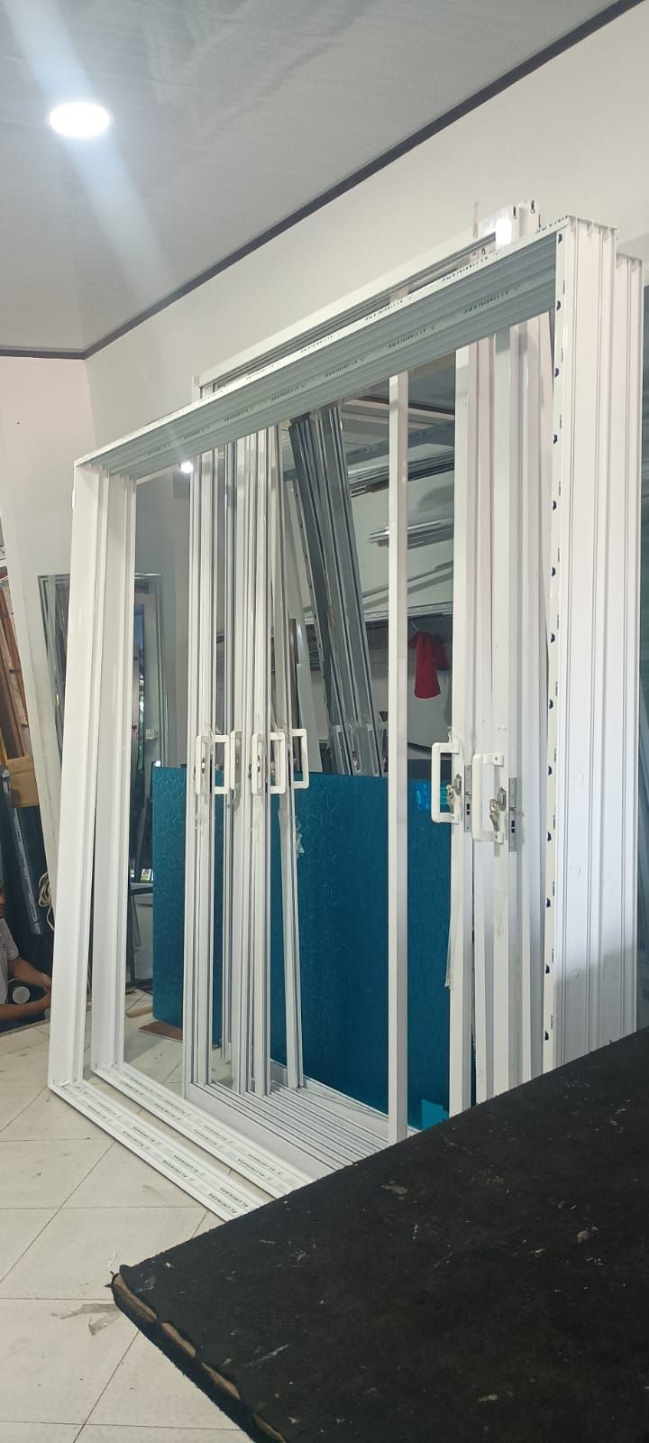 Oficina moderna con sala de conferencias con paredes de cristal y suelo de madera, que incluye puertas correderas de cristal.