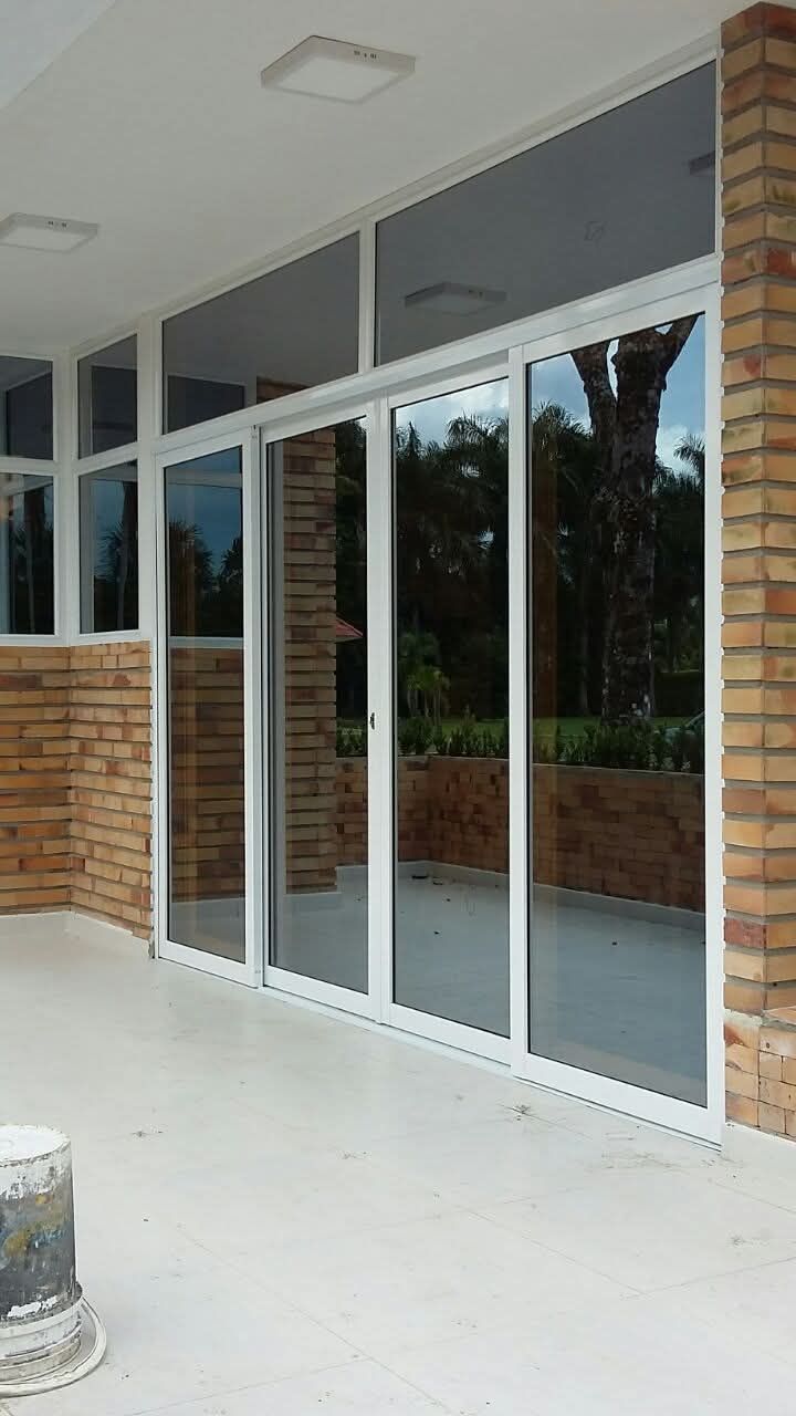 Habitación vacía con un gran ventanal que va desde el suelo hasta el techo y que da a árboles verdes y césped.