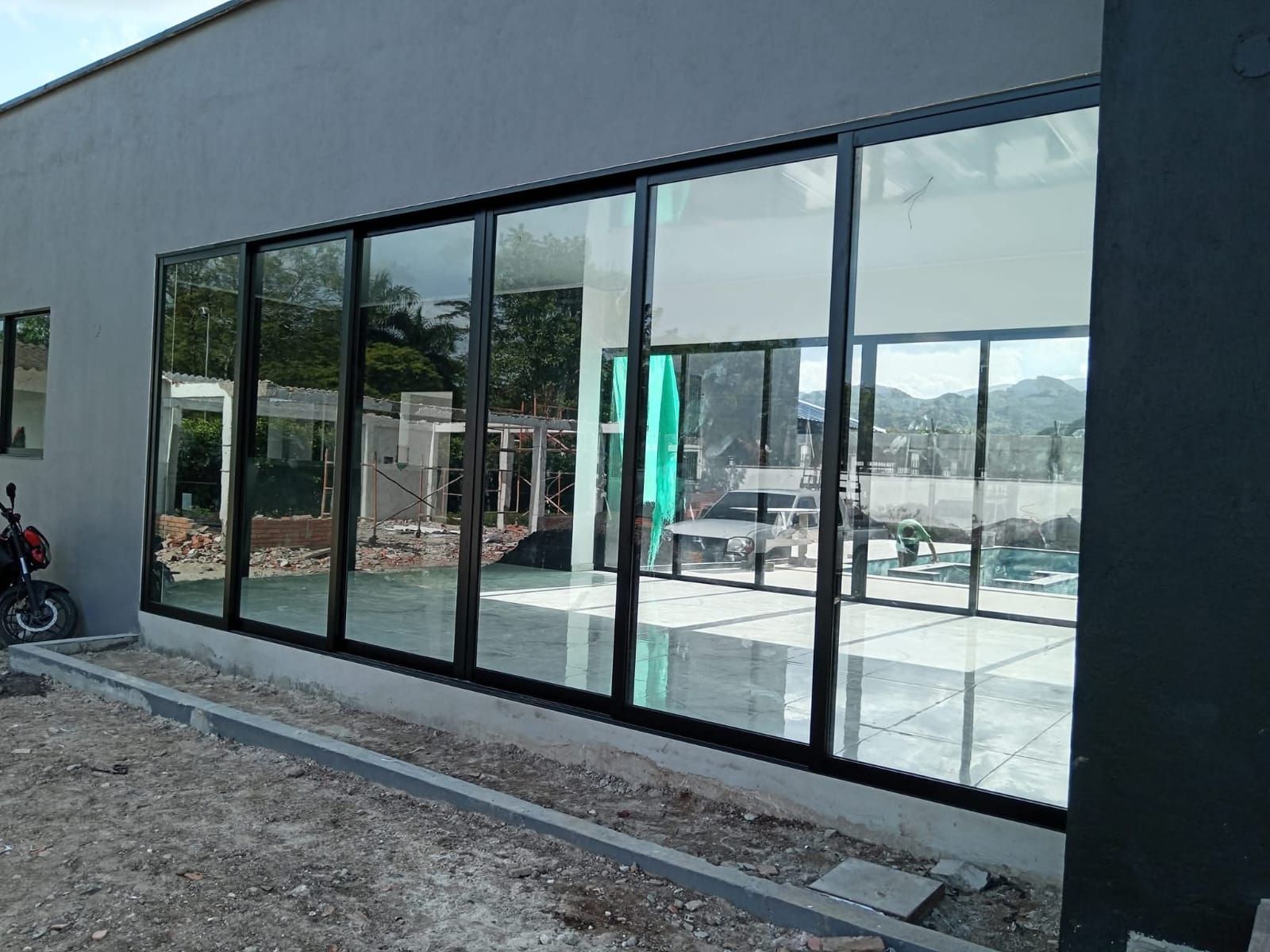 Estructura moderna de vidrio y acero en construcción, con columnas y vigas a la vista en el exterior.