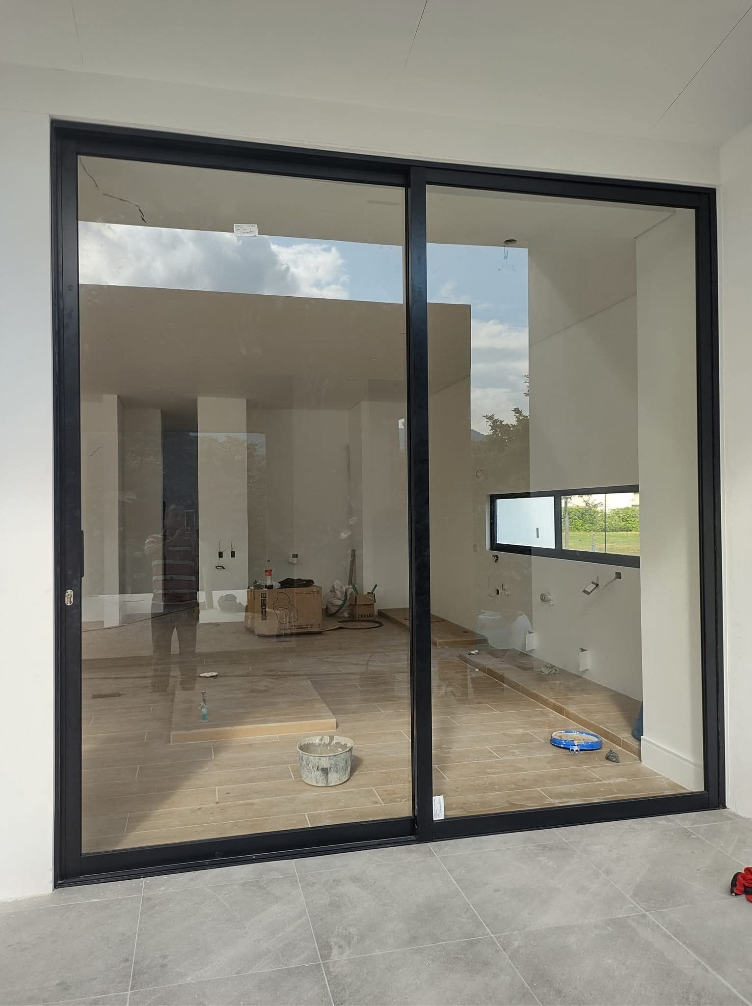 Sala de reuniones de oficina con paredes de cristal, puertas correderas y suelo de madera.