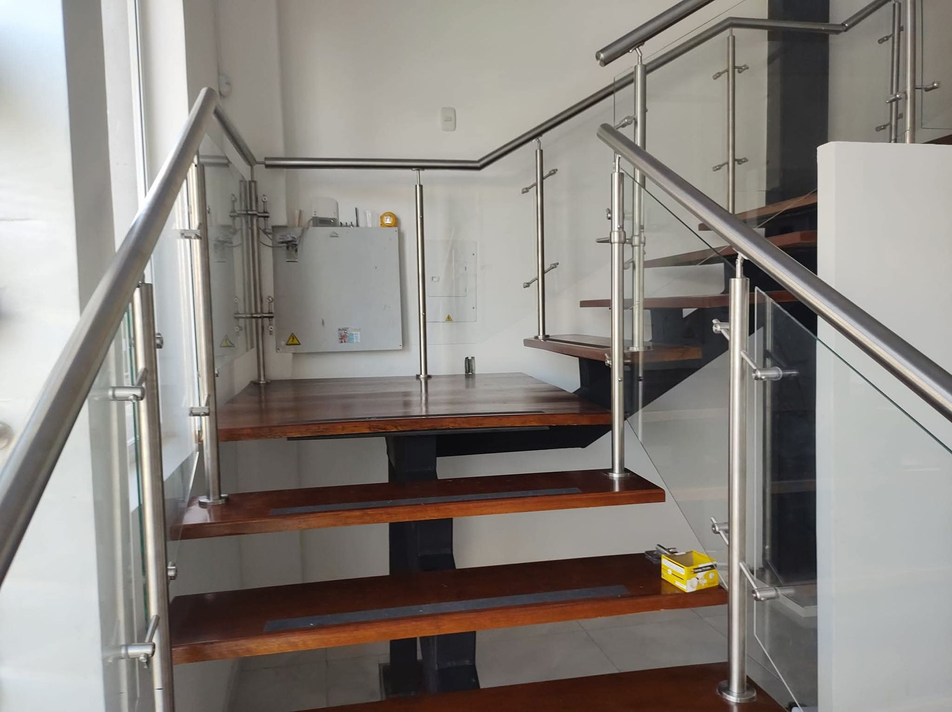 Escaleras de madera con barandillas metálicas en un luminoso pasillo interior.