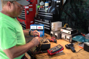 A man in a green shirt is working on an electronic device.