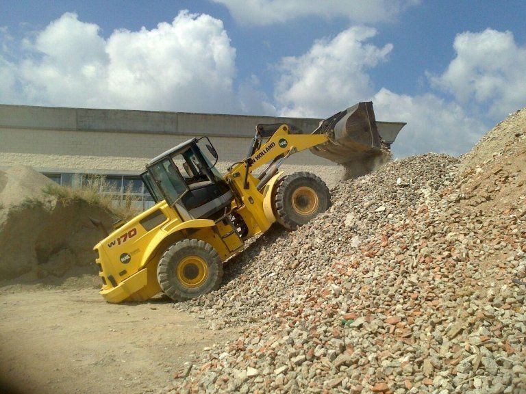Un bulldozer giallo sta guidando giù da un mucchio di rocce