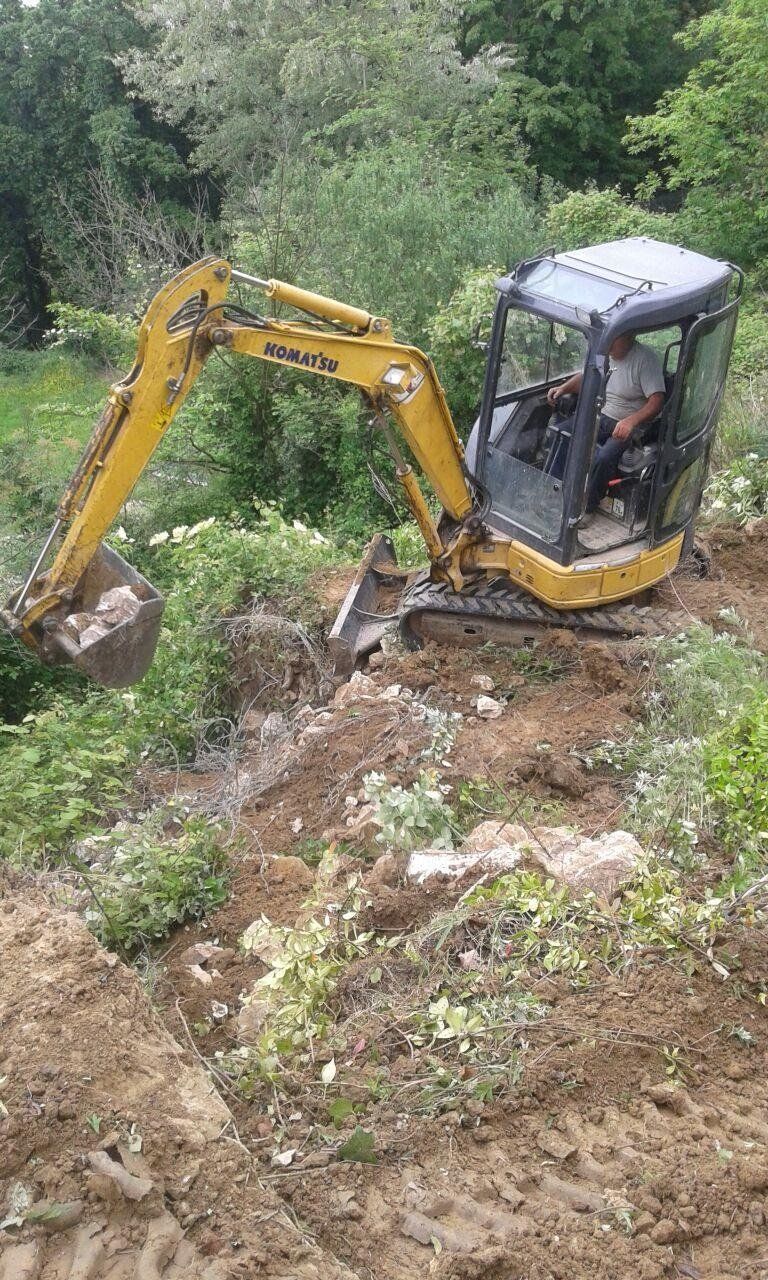 Un escavatore giallo sta scavando una buca nel terreno.