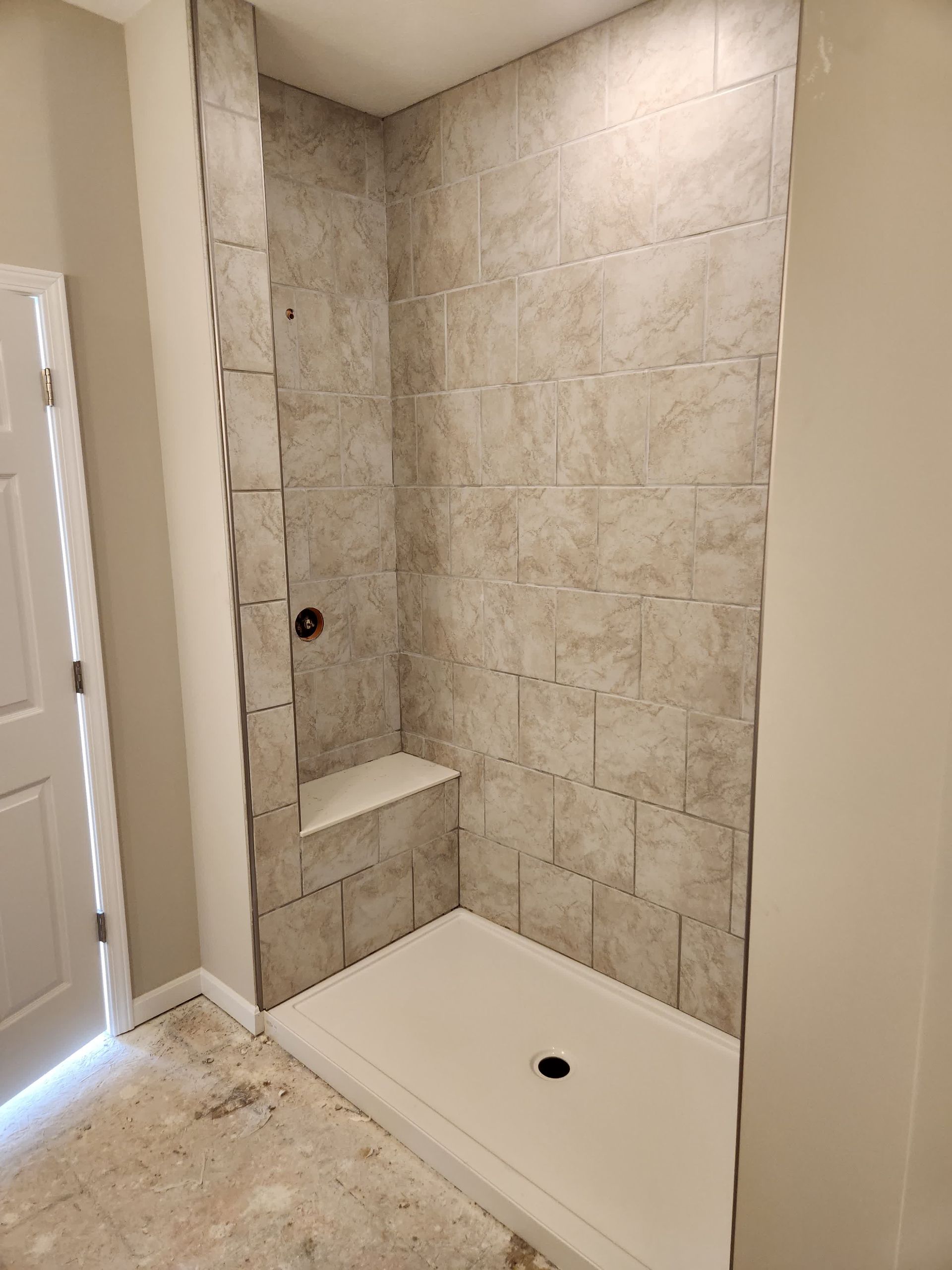 A bathroom with a walk in shower and a bench.