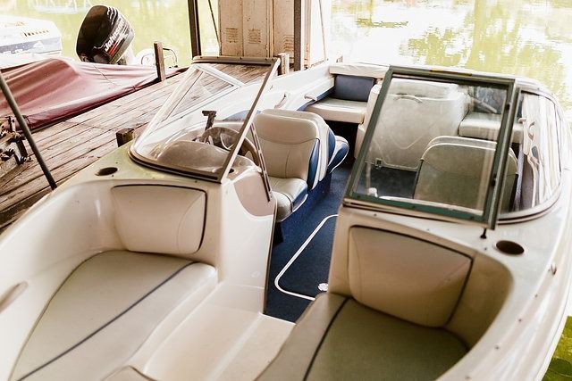 A small white motorboat docked in a covered boathouse, with tan and blue interior seating.