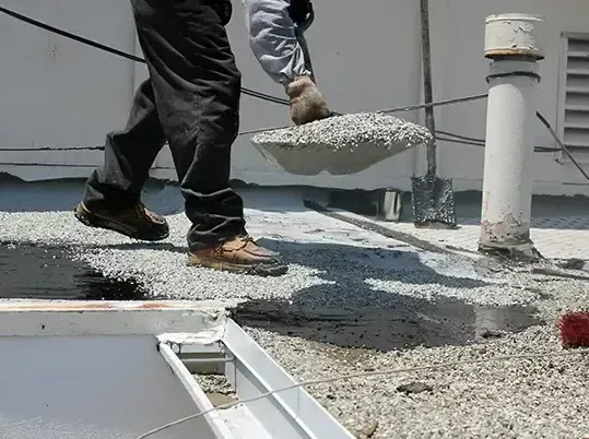 A man is pouring cement into a bucket on a roof.