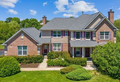 A large brick house with a gray roof and purple shutters