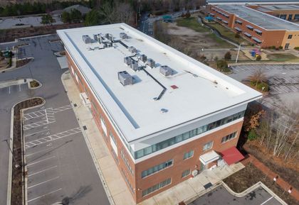 An aerial view of a large brick building with a white roof.