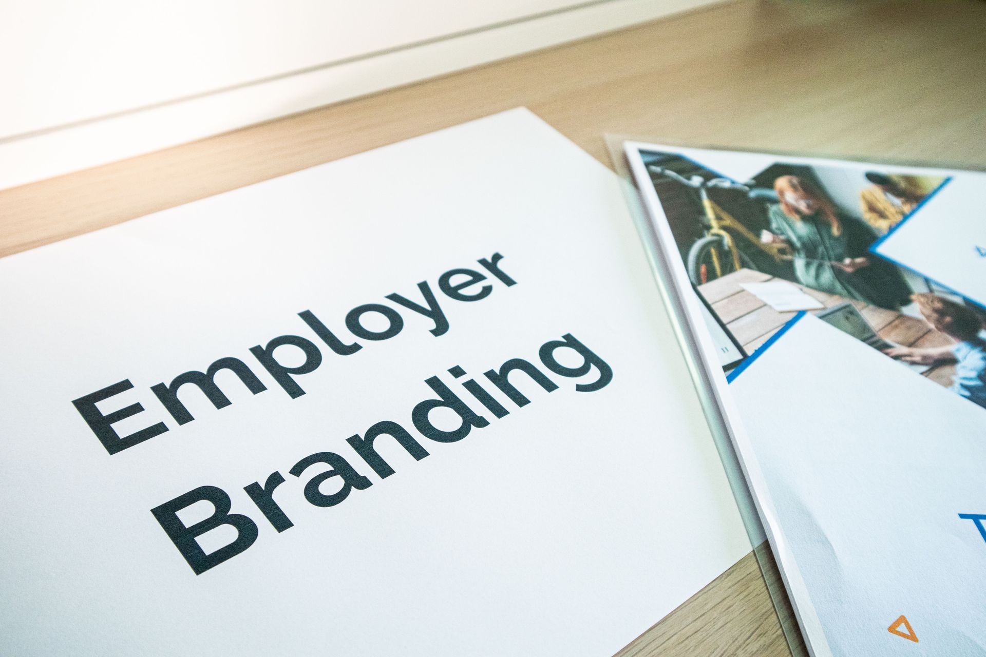 Employer Branding text on a white page beside a magazine with a business photo.