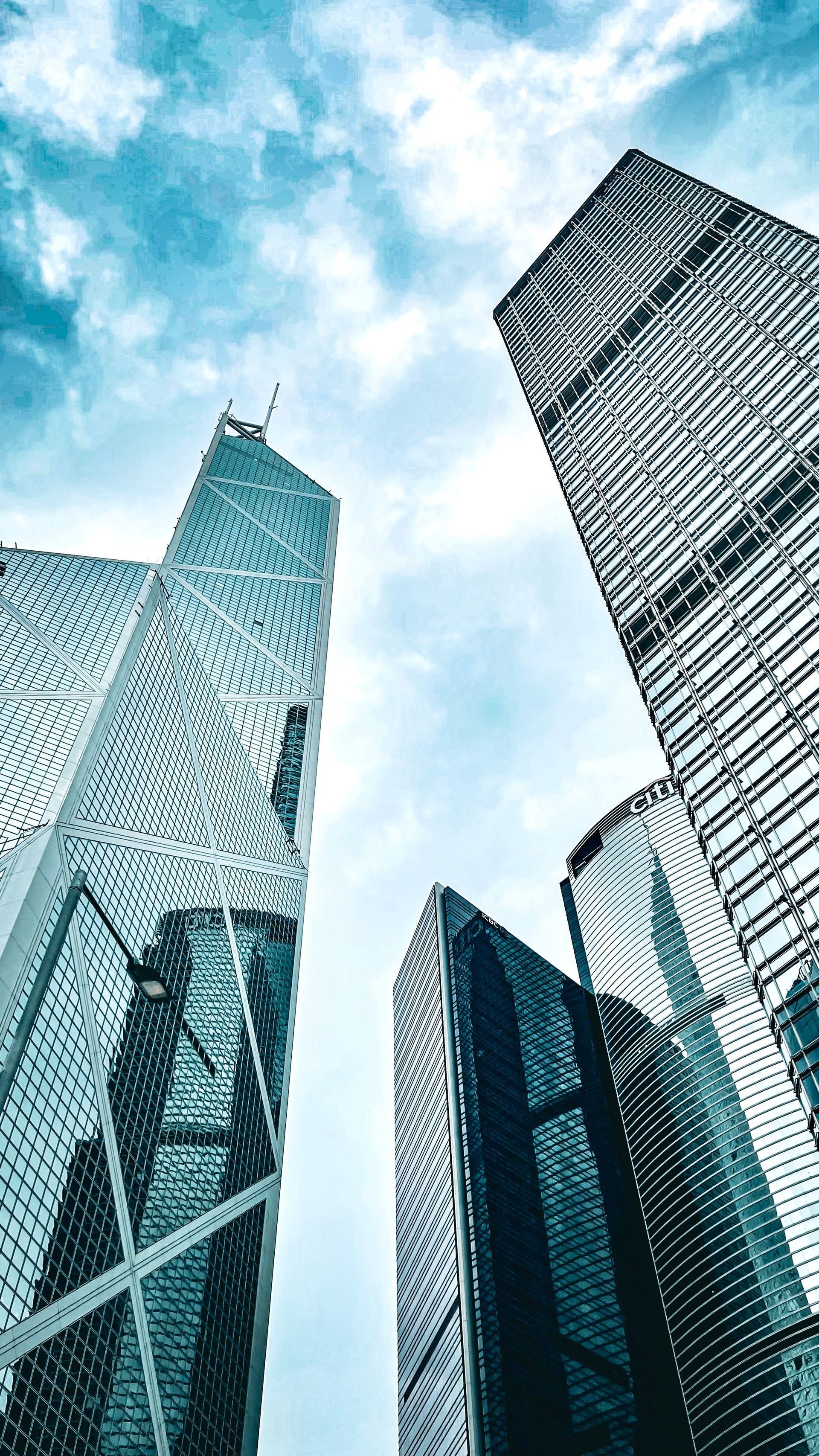 Skyscrapers seen from below against a bright blue sky with clouds