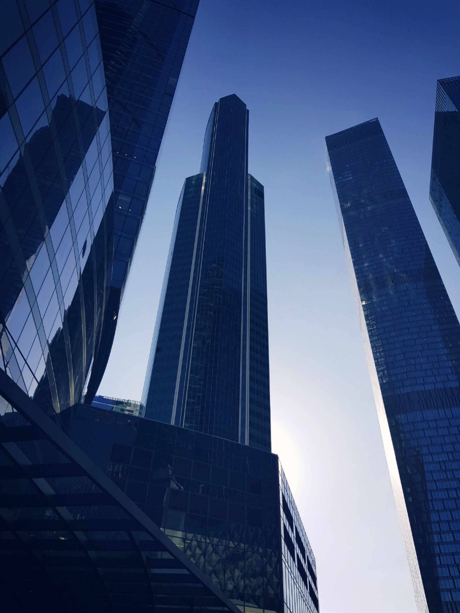 Tall glass skyscrapers against a blue sky, viewed from below in a city business district
