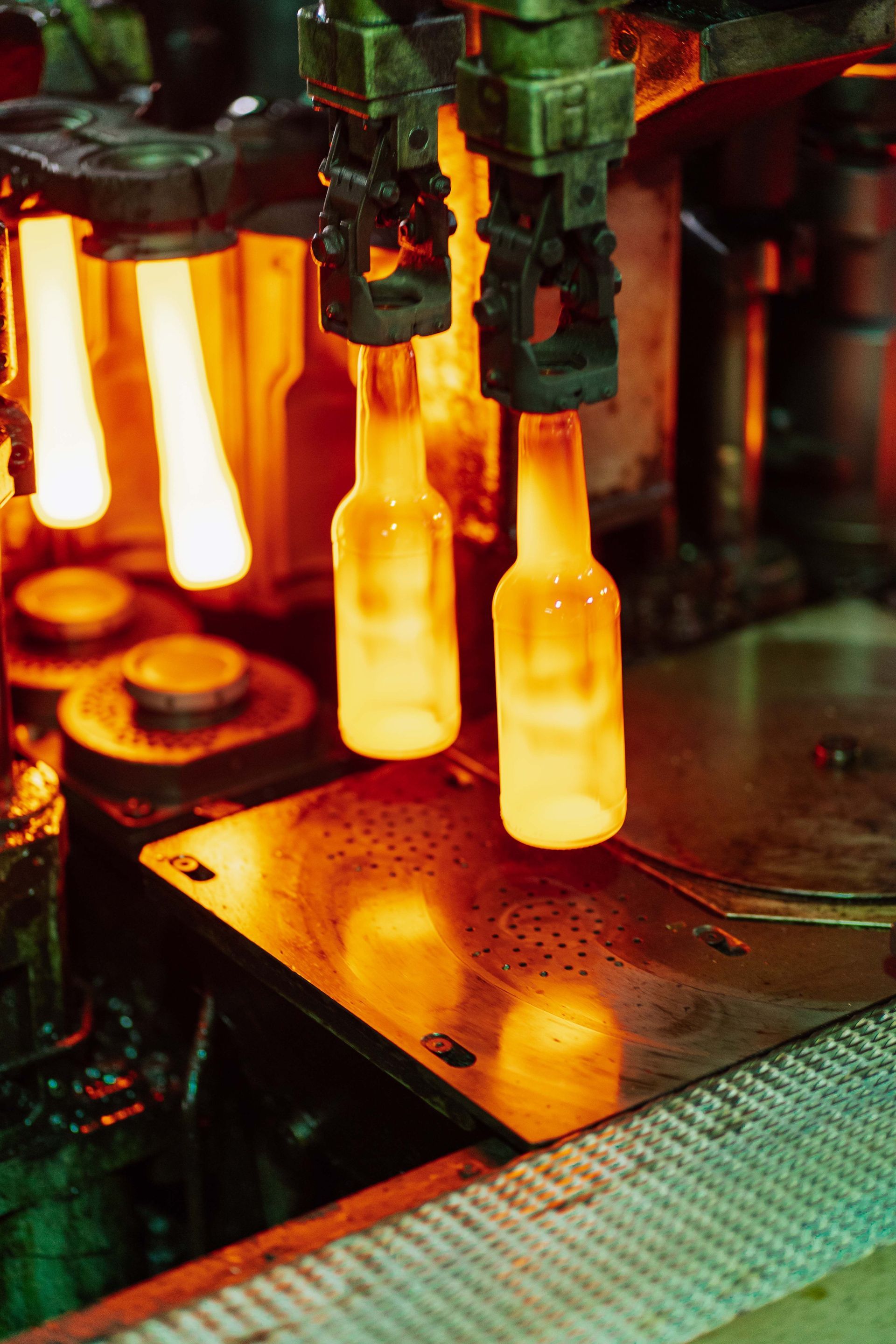 Glass bottles being molded in a glowing industrial factory machine
