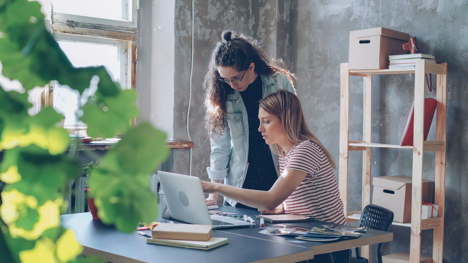 Two people collaborating at a desk with a laptop in a bright office space