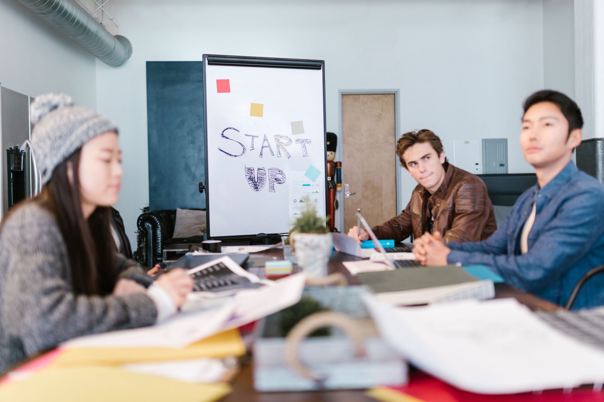 People meeting around a table in a bright office, discussing a presentation board with sticky notes.