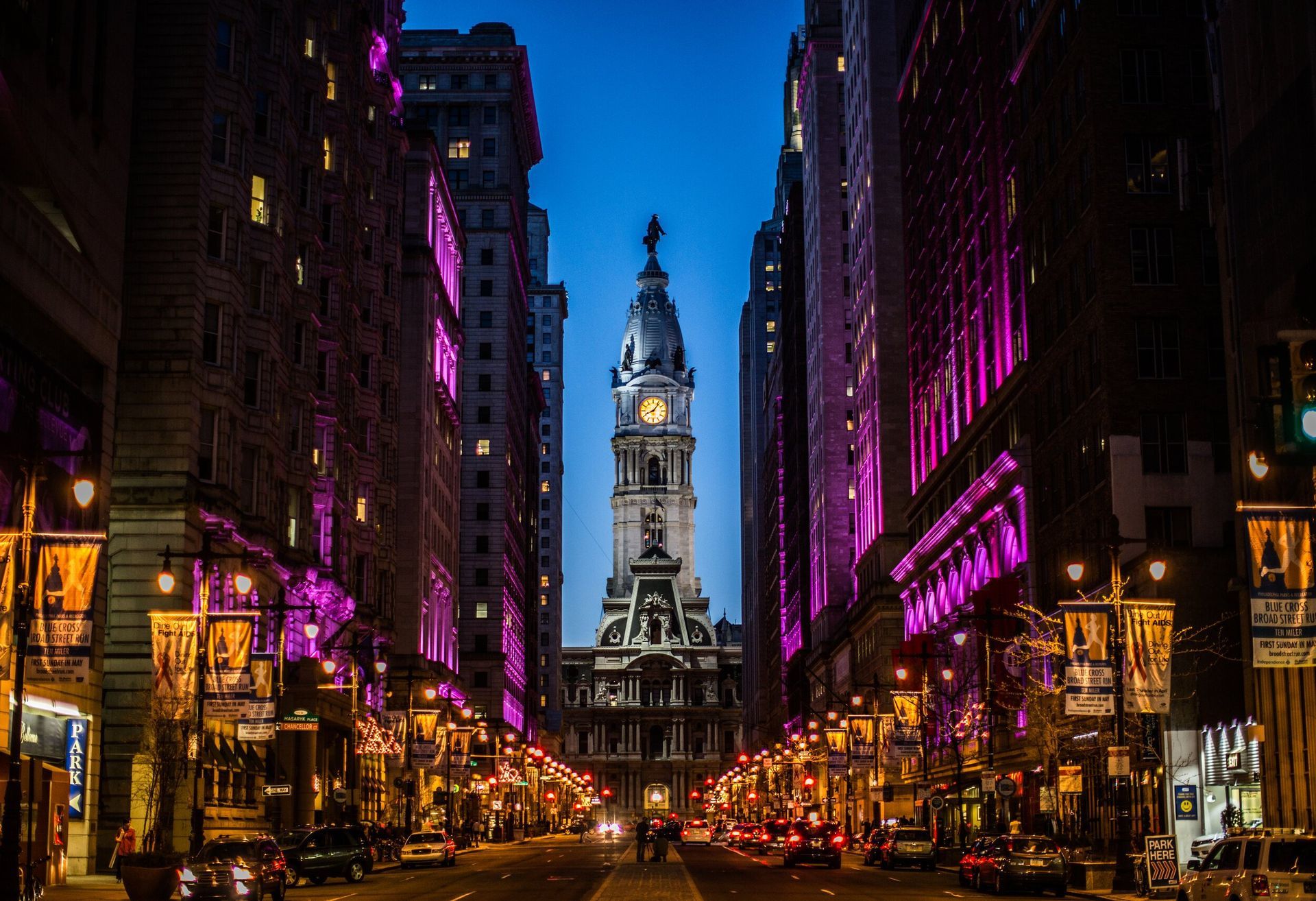 Philadelphia City Hall at dusk, framed by illuminated buildings and streetlights.