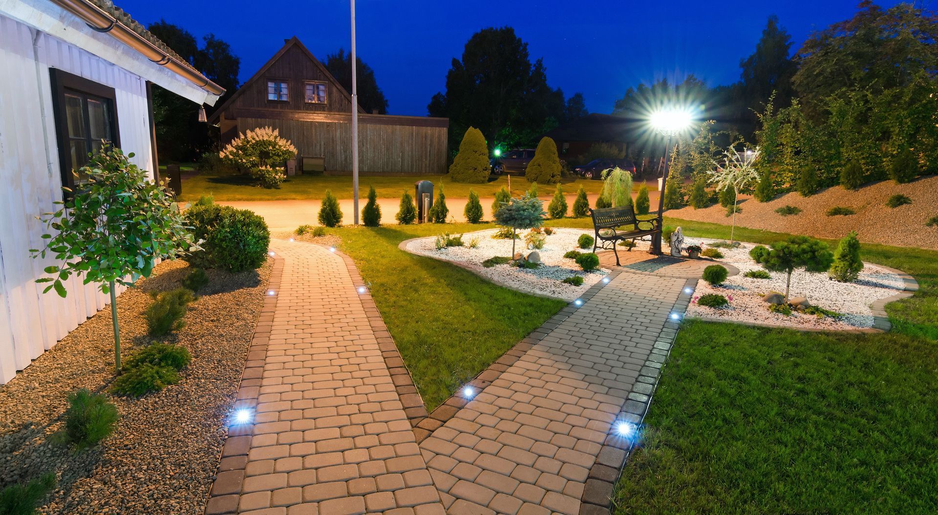 A brick walkway leading to a house at night