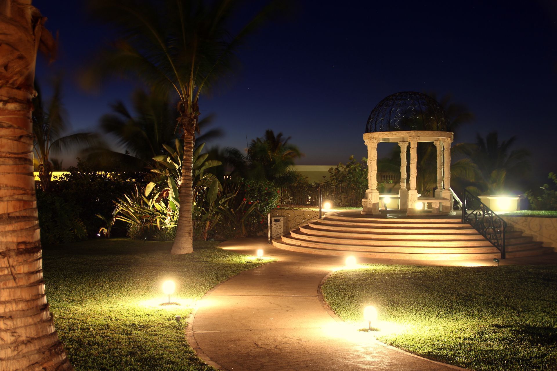 A gazebo is lit up at night in a garden