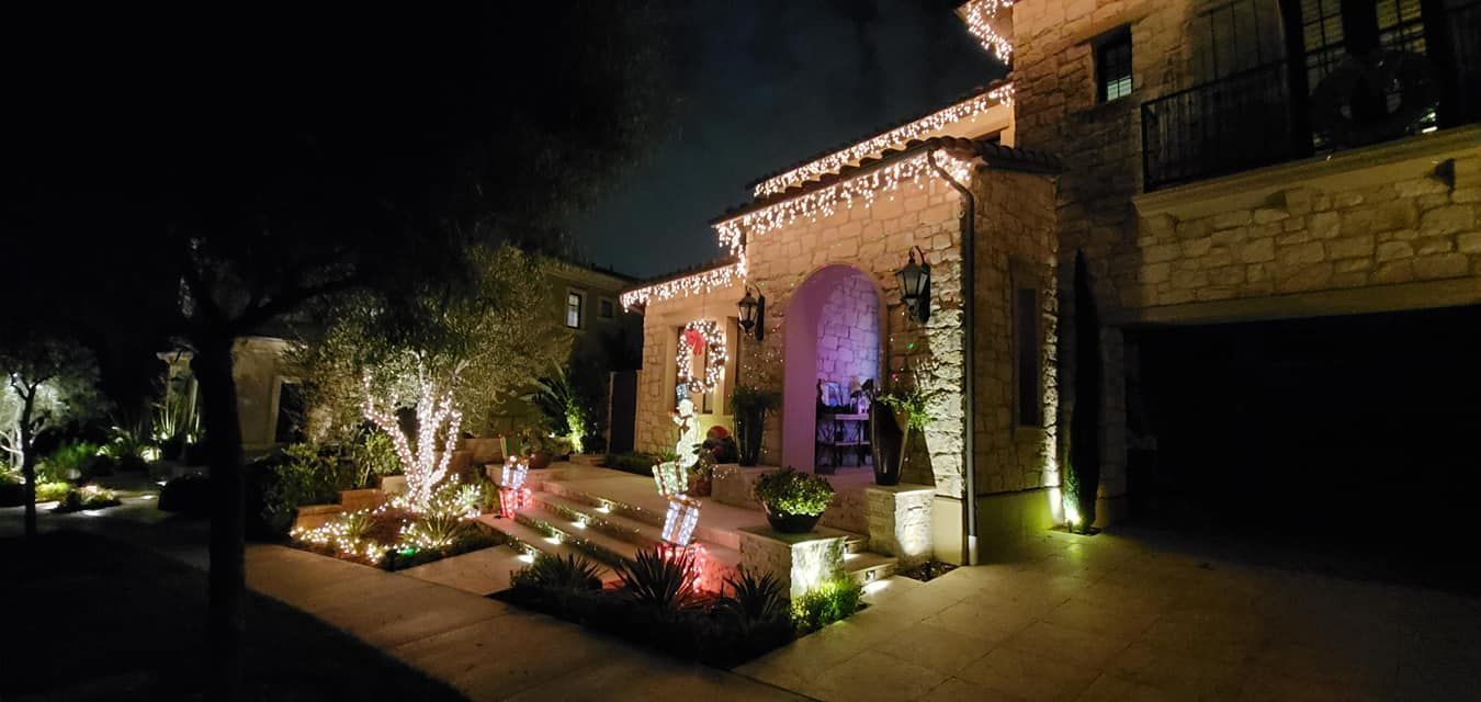 A large house is decorated with christmas lights at night.