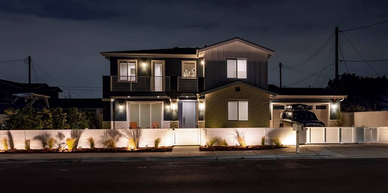 A house is lit up at night with a car parked in front of it