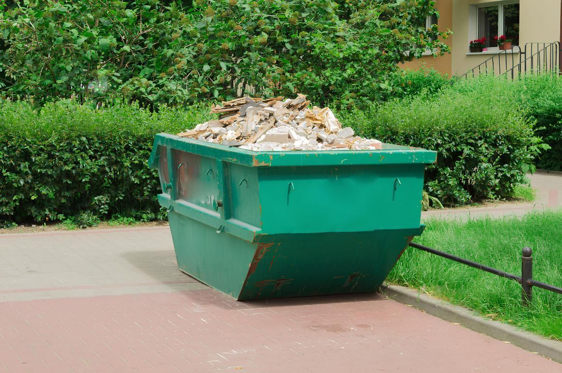A Green Dumpster Filled With Trash is Parked on the Side of the Road — I.B.S Skip Bins in Mapleton, QLD