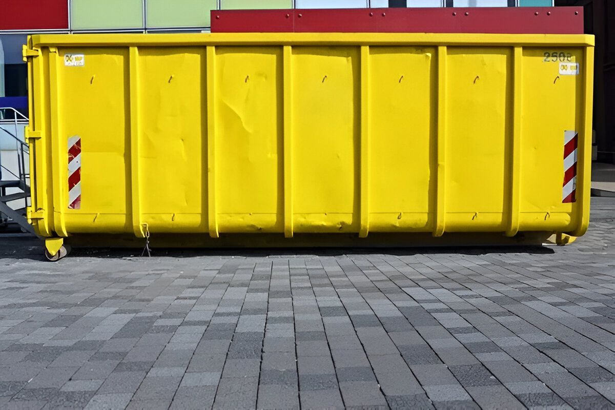 A Large Yellow Dumpster is Parked on a Brick Sidewalk — IBS Skip Bins in Currimundi, QLD