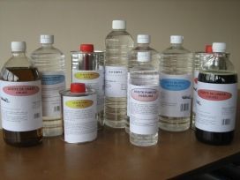 Varias botellas y frascos de productos químicos con etiquetas de colores dispuestos sobre una mesa de madera.