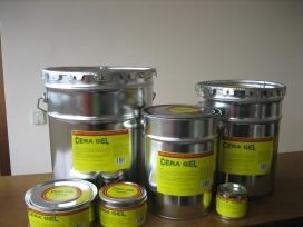 Latas y frascos de metal de CERA GEL amarillo sobre una mesa, con un pequeño recipiente abierto delante.