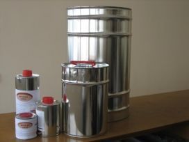 Bote de metal para la cocina y pequeños recipientes con tapa roja sobre una mesa de madera.