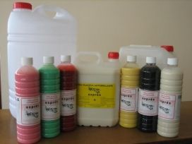 Varias botellas de plástico con líquidos de colores sobre una mesa, incluyendo envases rojos, verdes, amarillos, negros y blancos.