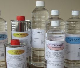 En un estante, botellas de plástico y metal surtidas de aceites y disolventes, con tapones blancos y rojos.