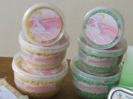 Montones de tarros de cosméticos de colores pastel con tapas rosas y verdes en un estante.
