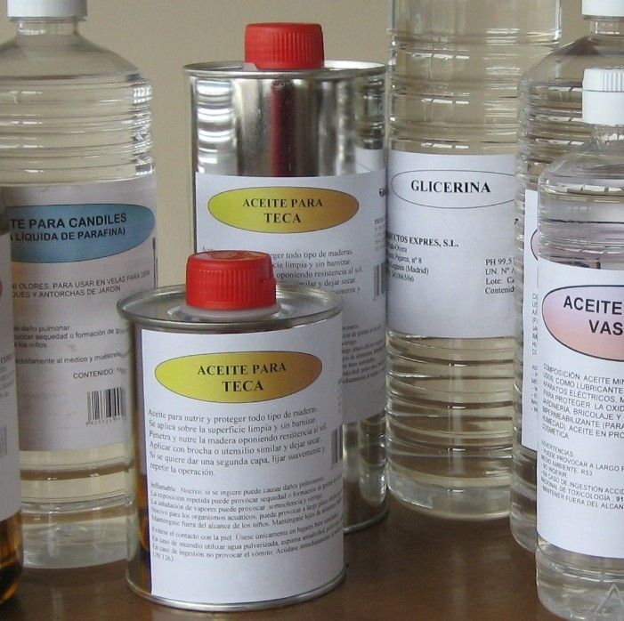 Surtido de botellas y latas de líquidos transparentes con etiquetas en español en un estante.