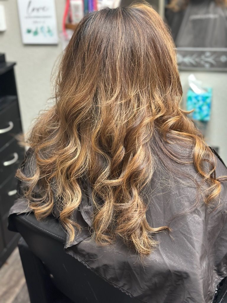 Back view of long wavy brown hair with highlights in a salon chair