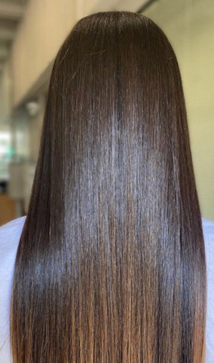 The back of a woman 's hair is very straight and shiny.
