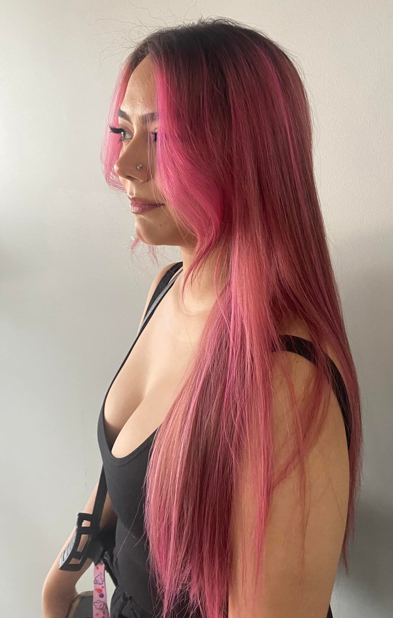 A woman with long pink hair is wearing a black dress.