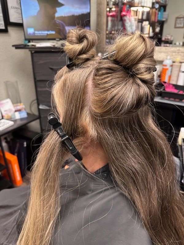 Hair salon client with half-up top knots and a large hair clip, viewed from behind.