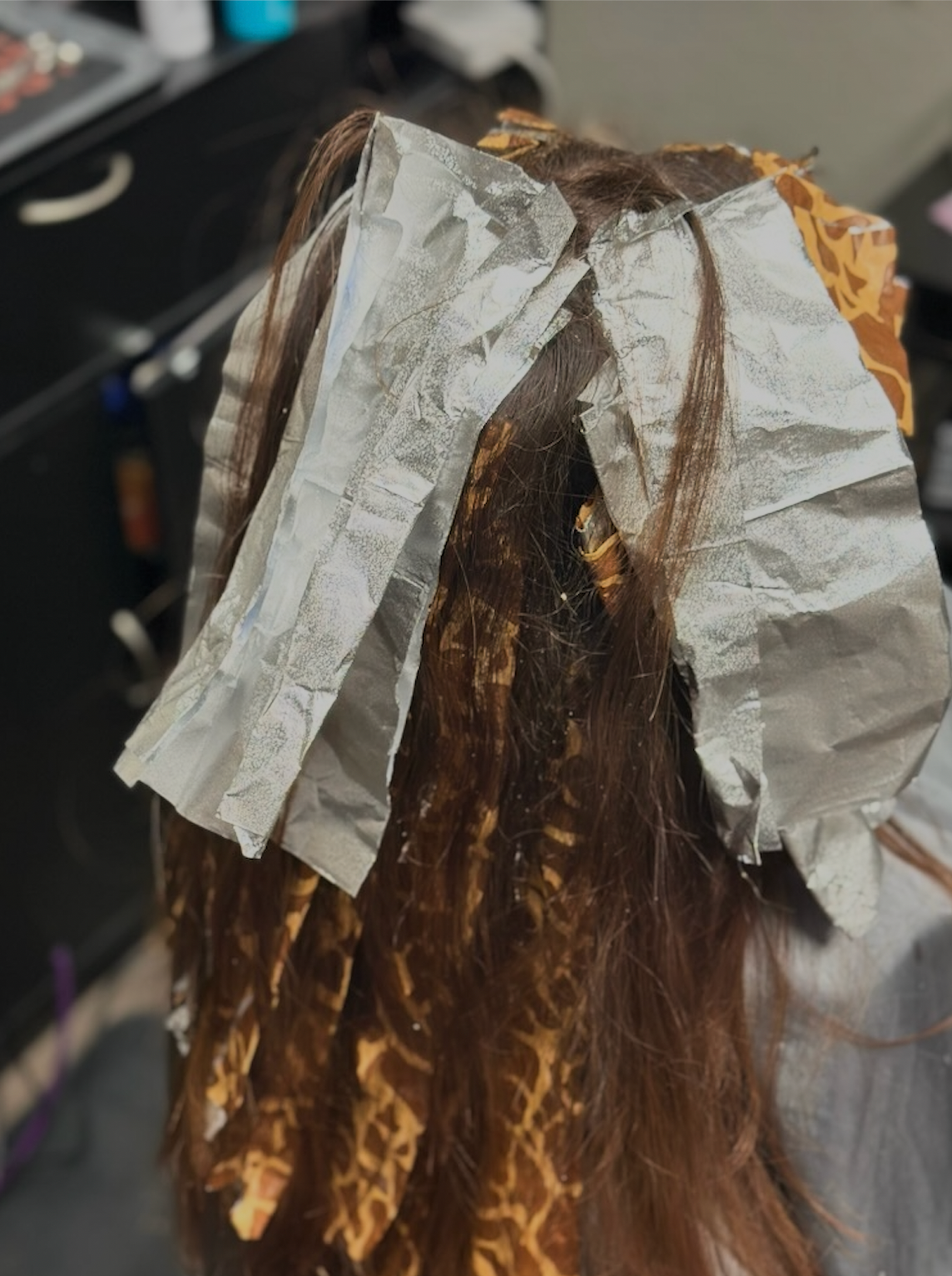 Hair sectioned with silver foil highlights in a salon chair