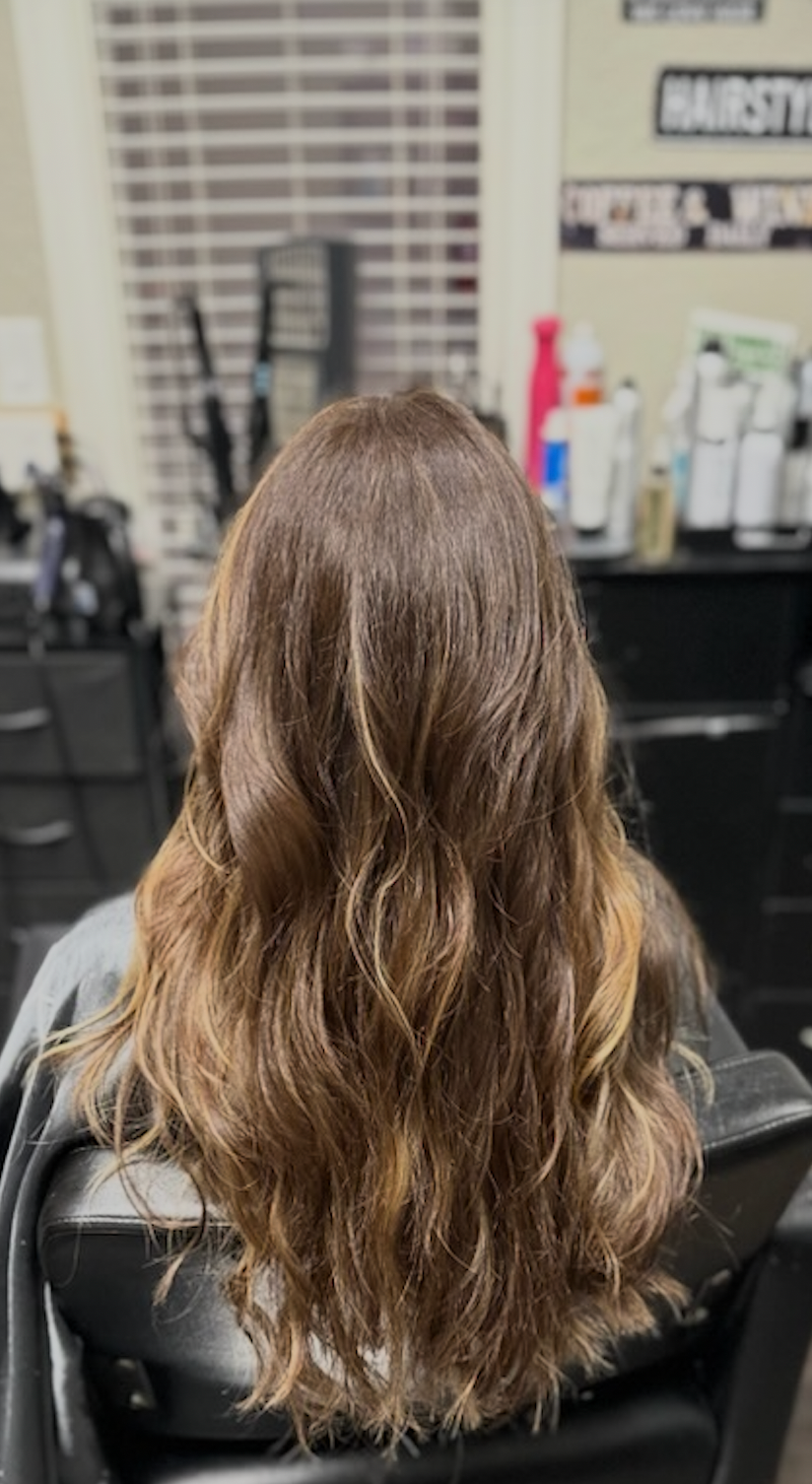 Long wavy light-brown hair viewed from behind in a salon chair.