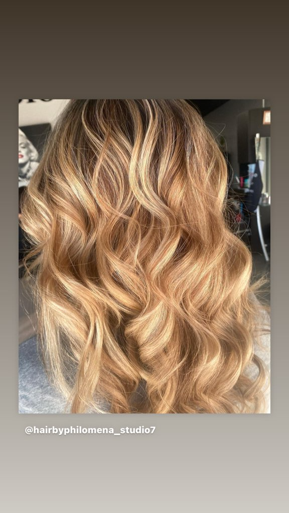 Long, wavy blonde hair with dark roots, styled in loose curls from back view.