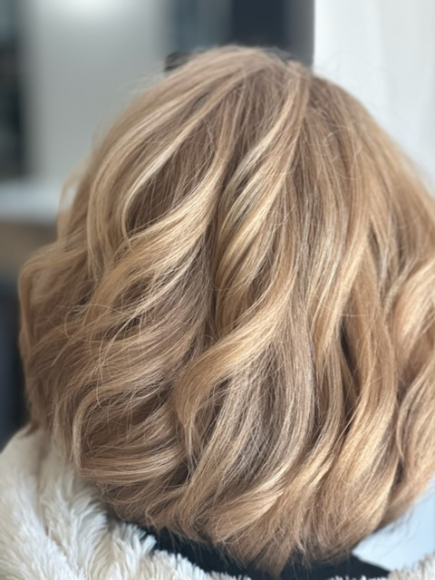 Close-up of short, layered wavy blonde hair from the back
