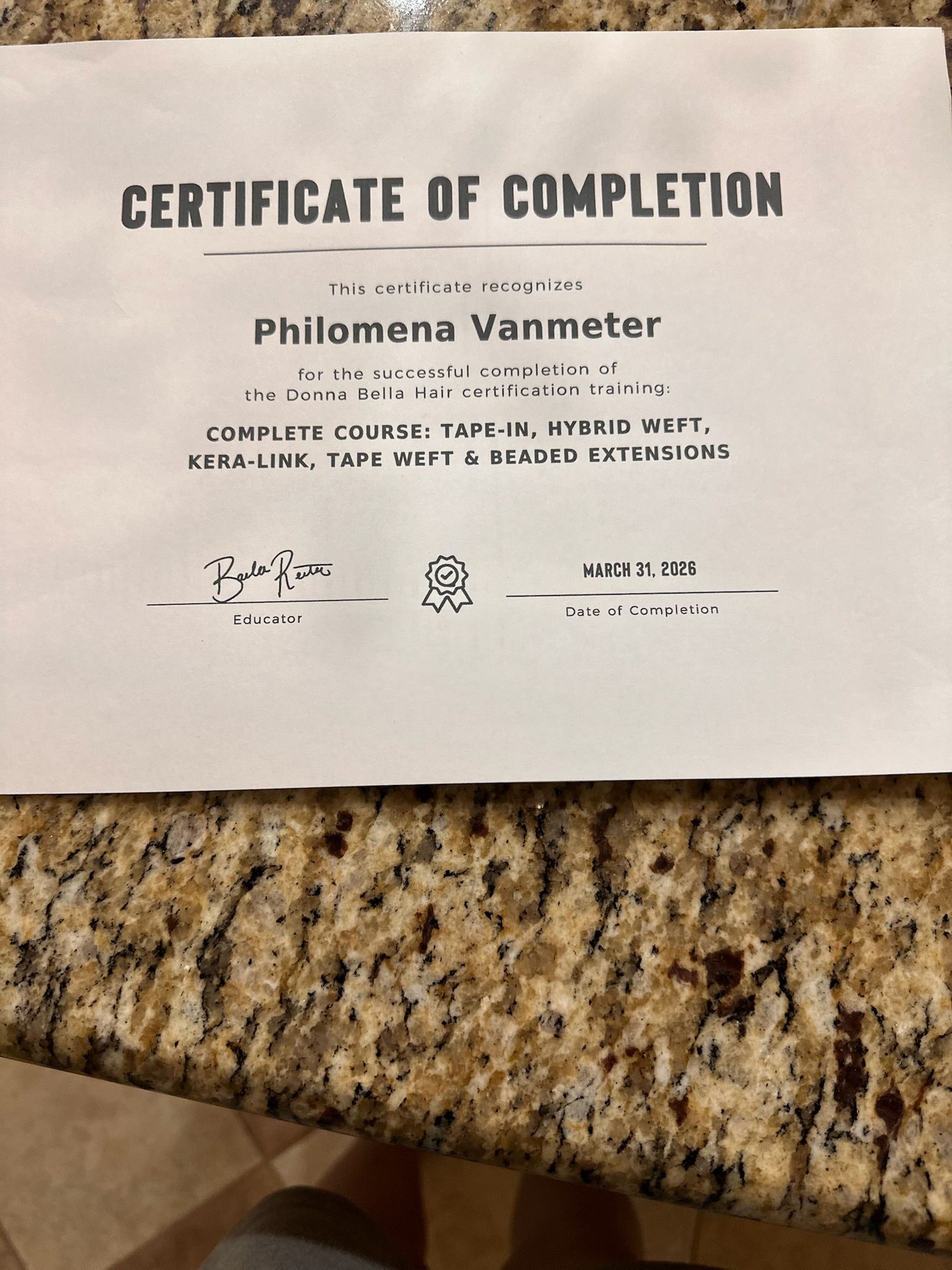Certificate of completion on a granite countertop, with the name Philomena Vanmeter visible.