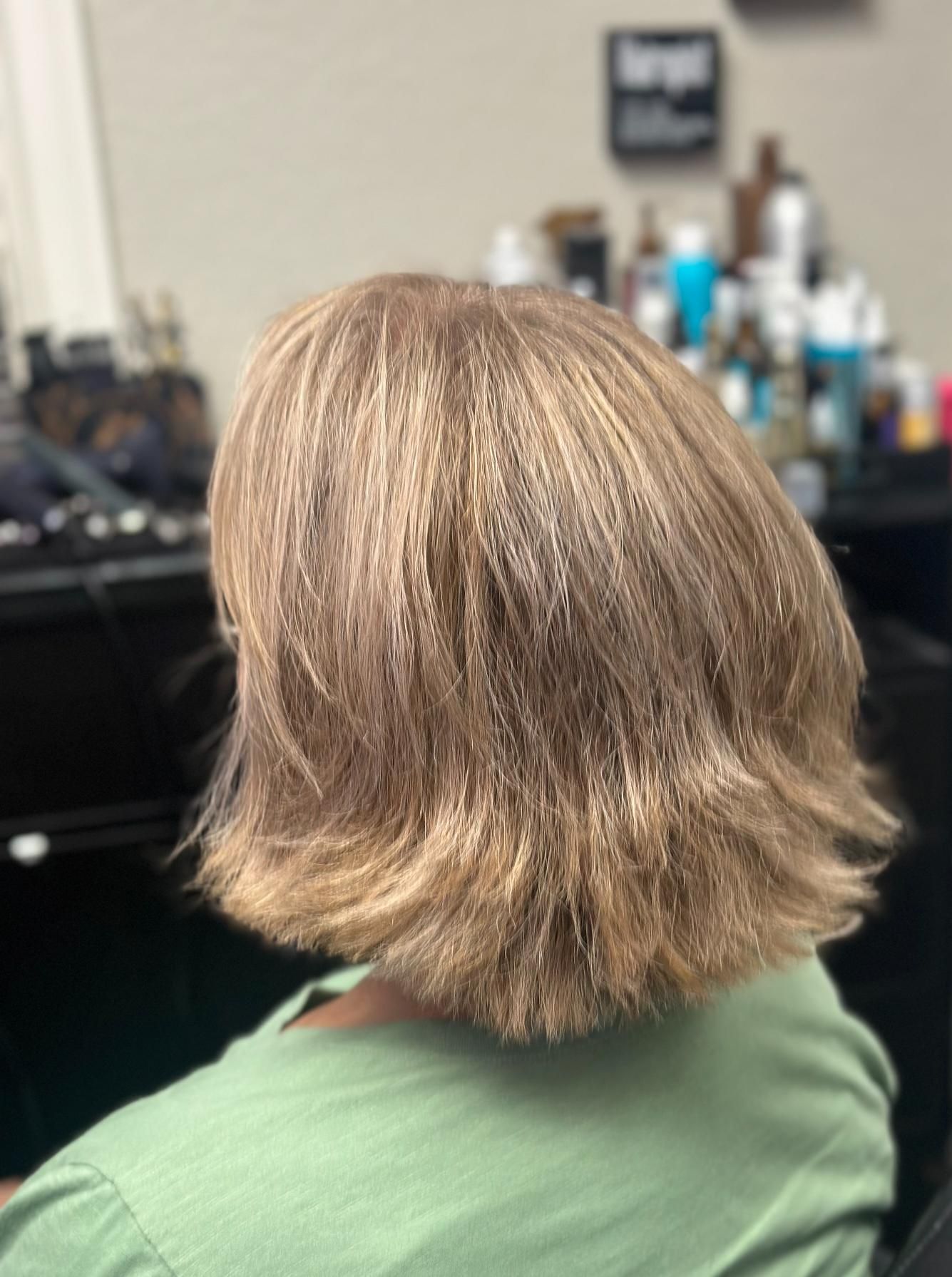 Short layered blonde-brown haircut shown from the back in a salon chair