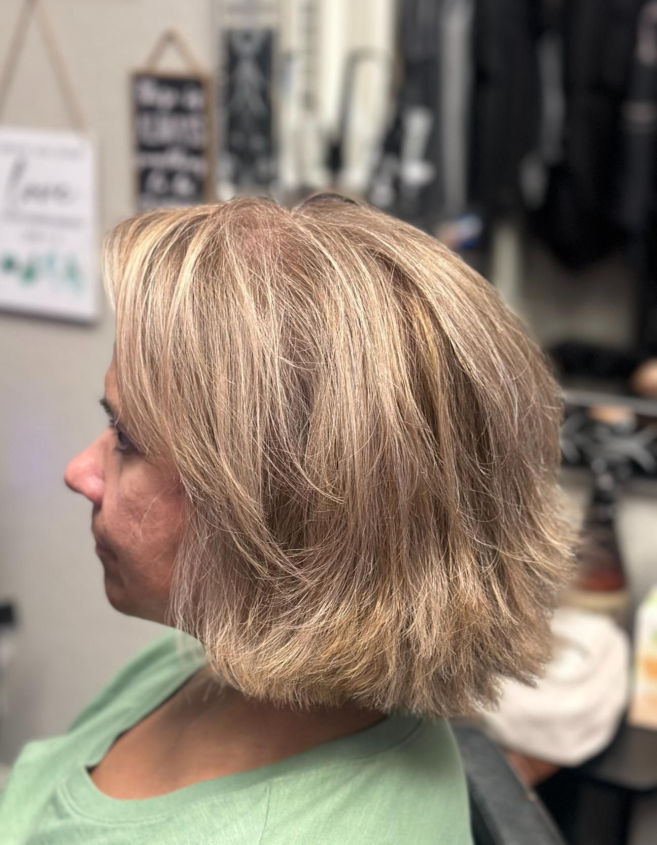 Profile view of a short blonde layered haircut in a salon chair