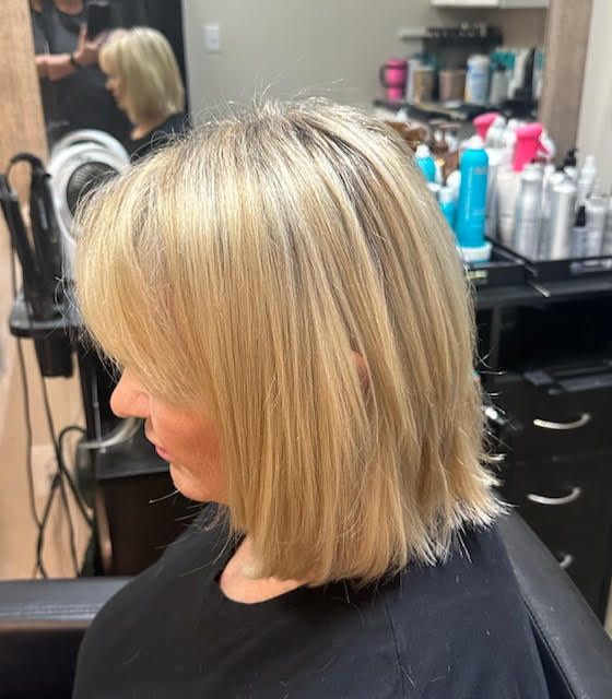 A woman with blonde hair is sitting in a chair in a salon.
