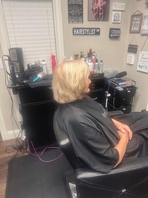 A woman is sitting in a chair in a hair salon.
