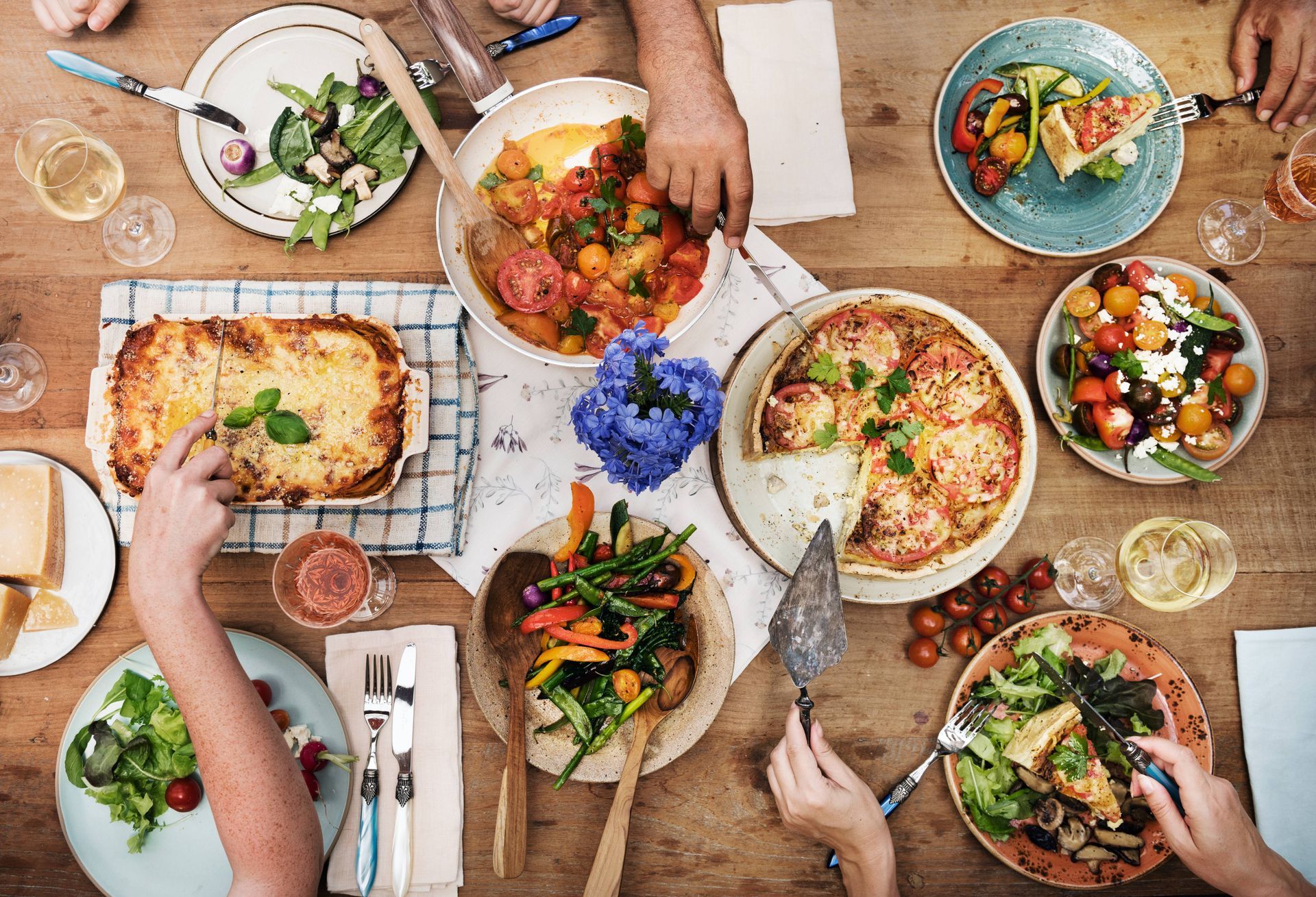 Top view of a wood dinner table with various plates of food