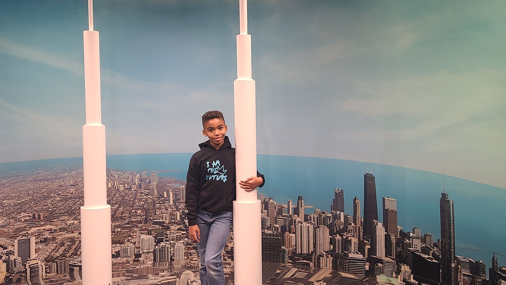A young boy is standing in front of a city skyline.