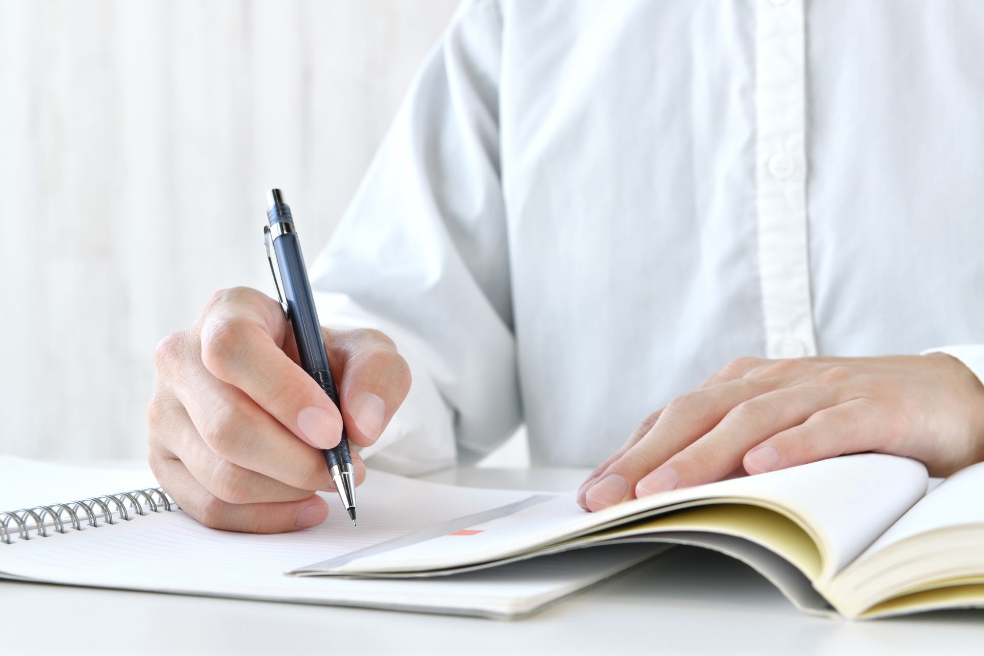 A person is writing in a notebook with a pen.